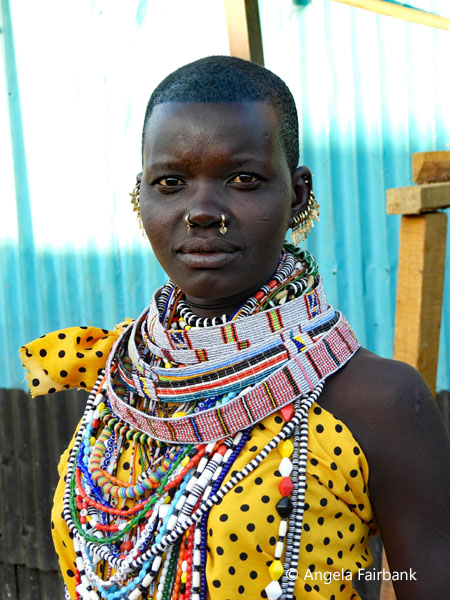 Toposa woman in yellow with black polka dots at market