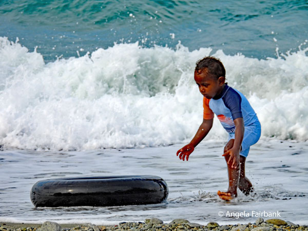boy in water chasing rubber tire