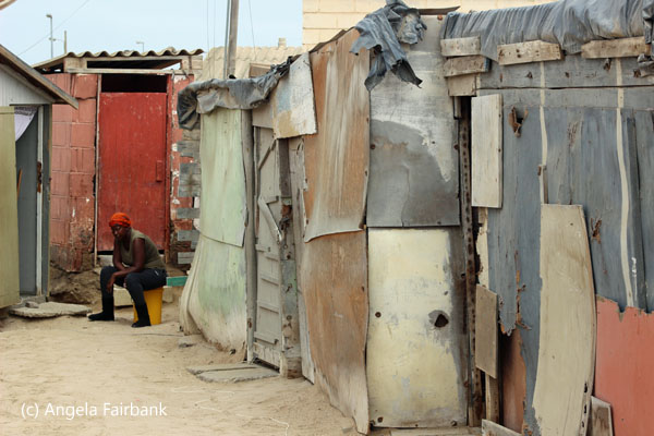 woman sitting in yard with tin sheet building