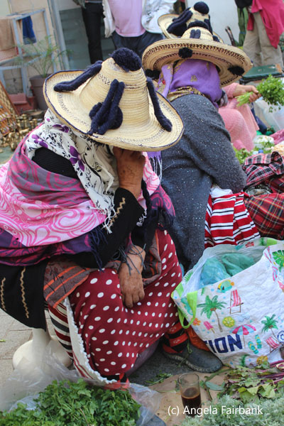 female vendors in pompom-ed straw hats