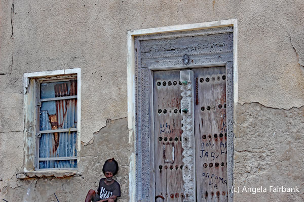 man sitting by omani door